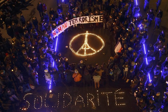 epa05025544 People gather around a symbol of the Eiffel Tower created with lighted candles during a rally in honor of the victims of the terrorist attacks in Paris, in Lausanne, Switzerland, 14 Novemb ...