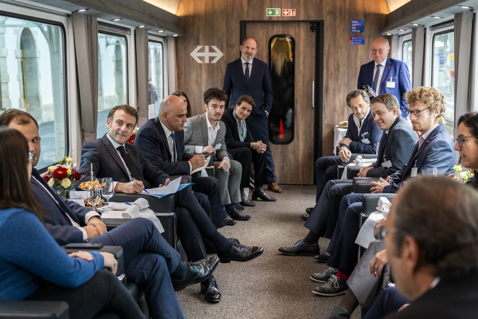 French President Emmanuel Macron, left, and Swiss President Alain Berset, right, speak during a discussion with start-up representatives, on board the special train, Switzerland, Thursday, 16 November ...
