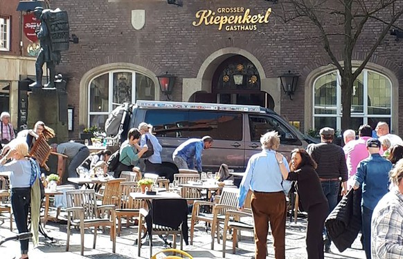 People stay in front of a restaurant in Muenster, Germany, Saturday, April 7, 2018 after a vehicle crashed into a crowd killing four people and injuring 20 others. The German news agency dpa has quote ...