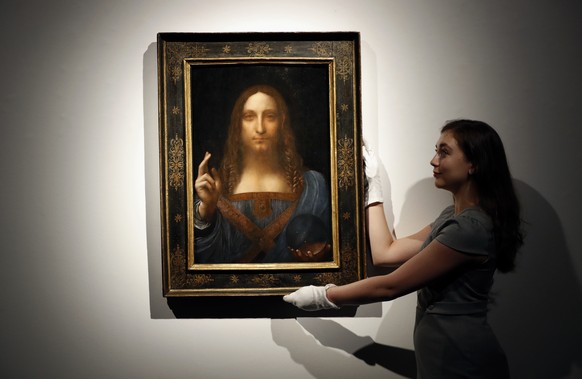 FILE - In this Oct. 24, 2017 file photo, an employee poses with Leonardo da Vinci&#039;s &quot;Salvator Mundi&quot; on display at Christie&#039;s auction rooms in London. Abu Dhabi’s Department of Cul ...