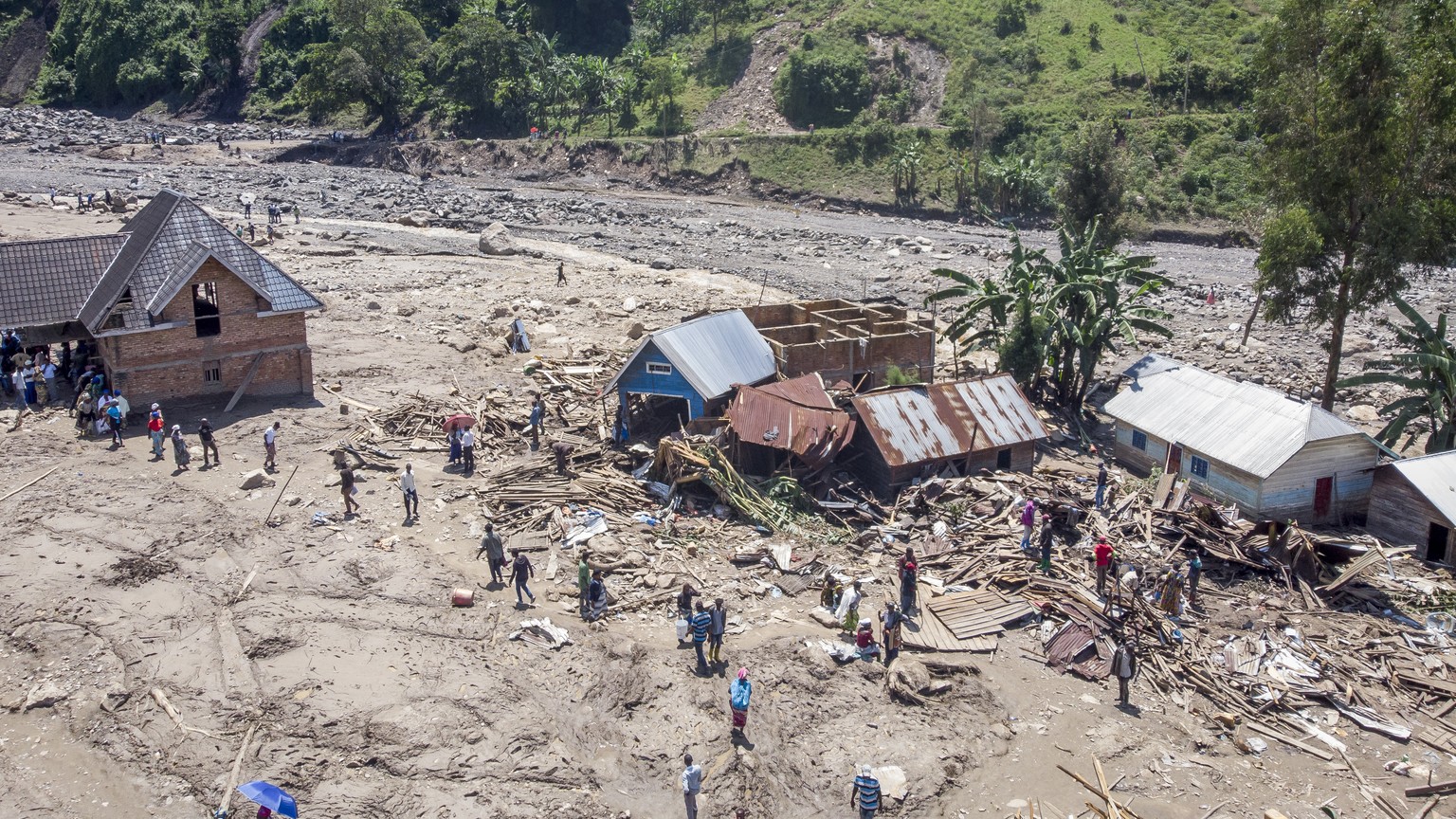 Survivors walk amidst debris next to destroyed buildings in the aftermath of floods in the village of Nyamukubi, South Kivu province, in Congo Monday, May 8, 2023. The death toll from floods in easter ...