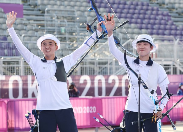 epa09361283 South Korean archer Kim Je-deok (L) celebrates with his teammate An San after winning the gold medal in the mixed team event at the Tokyo Olympics at Yumenoshima Park Archery Field in Toky ...