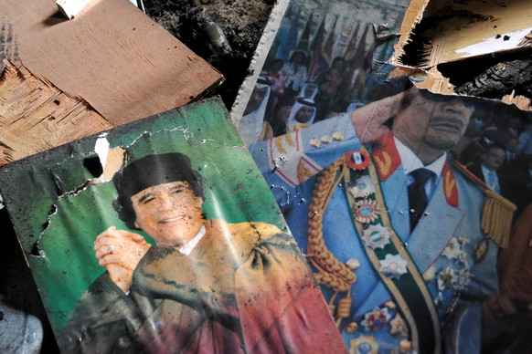 epa09016605 (FILE) - (11/26) Some defaced pictures of Libyan leader Muammar Gaddafi are seen in the southwestern town of Nalut, Libya, 28 February 2011 (Reissued 16 February 2021). On 17 February 2011 ...
