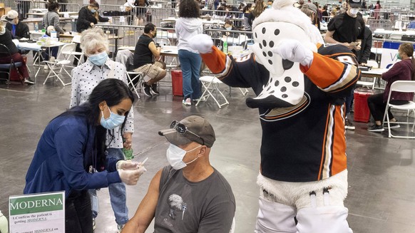 March 23, 2021, Anaheim, California, USA: Anaheim Ducks mascot Wild Wing celebrates with Peter Catellier as he receives a COVID-19 shot at the Anaheim Convention Center in Anaheim, CA on Tuesday, Marc ...