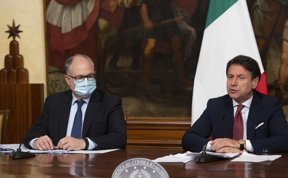 Italian Prime Minister, Giuseppe Conte, right, with Economy Minister Roberto Gualtieri, left, announces the latest set of measures under another emergency decree during the coronavirus pandemic, Frida ...