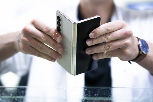 A Samsung worker tests a Samsung Fold Z 4 waterproof phone during the Mobile World Congress 2023 in Barcelona, Spain, on Wednesday, March 1, 2023. After three years of pandemic disruption, MWC, also k ...