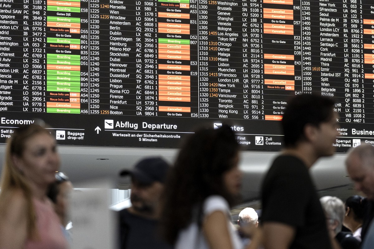 epa11487356 Passengers look at screens informing on the flight situation at the Zurich Airport in Kloten, Switzerland, 19 July 2024. Due to a major worldwide IT outage, check-in for air travelers and  ...