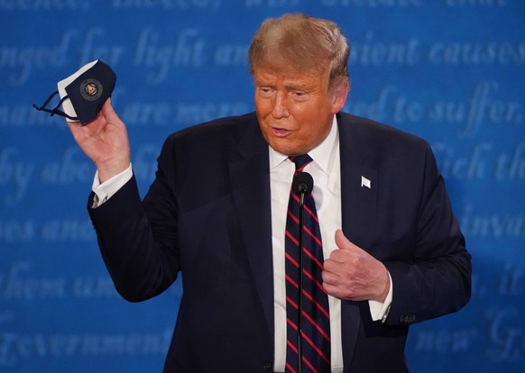 President Donald Trump holds up a face mask during the first of three scheduled 90 minute presidential debates with Democratic presidential nominee Joe Biden, in Cleveland, Ohio, on Tuesday, September ...