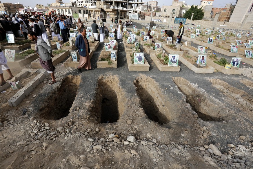 epa06797582 Yemenis walk among graves as people bury the bodies of Houthi militia members allegedly killed during recent fighting at Yemen’s western coast areas, during the funeral procession at a cem ...