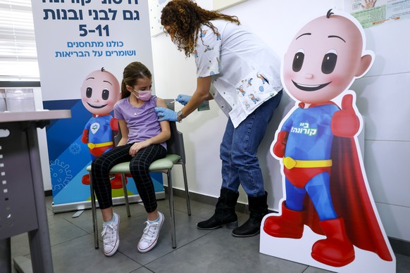 Israeli girl Danae Vitkin, 9, receives her first Pfizer-BioNTech COVID-19 vaccine from medical staff at Clalit Health services in Tel Aviv, Israel, Tuesday, Nov. 23, 2021. Israel begins coronavirus va ...