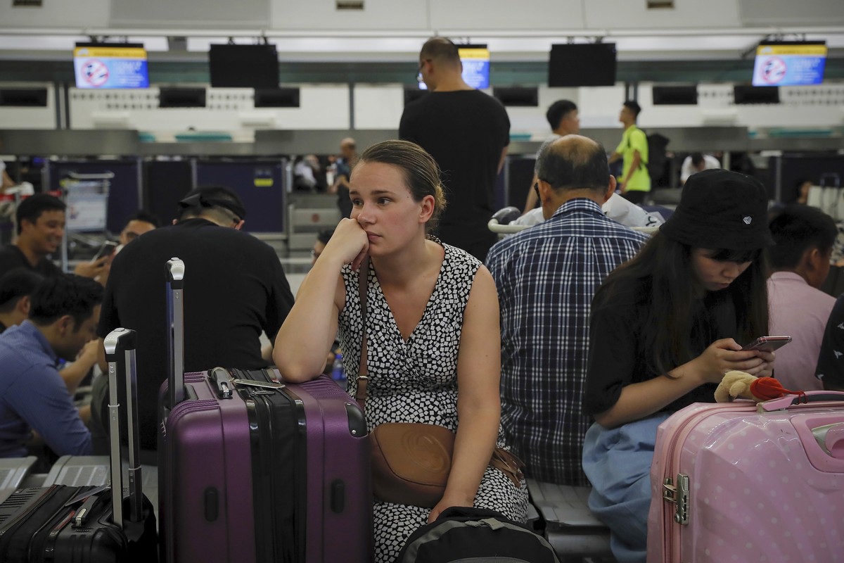 Australian Penny Tilley, center, reacts next to stranded travelers at the closed check-in counters at the Hong Kong International Airport, Monday, Aug. 12, 2019. One of the world's busiest airpor ...