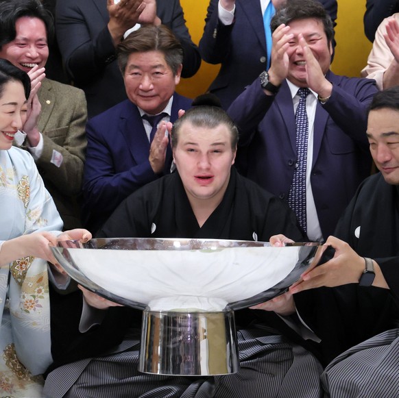 epa12544094 Ukrainian sumo wrestler Aonishiki (C) a large sake cup after he won the Kyushu Grand Sumo Tournament in Fukuoka, southwestern Japan, 23 November 2025. Aonishiki became Ukraine&#039;s first ...