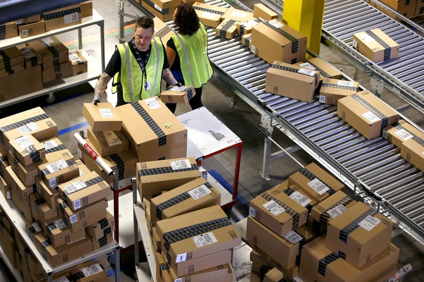 Amazon-Mitarbeiter sortieren Pakete.
