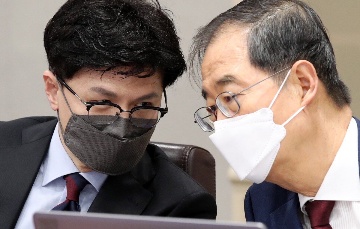 epa10116667 Prime Minister Han Duck-soo (R), and Justice Minister Han Dong-hoon talk during an emergency Cabinet meeting on presidential pardons three days ahead of Liberation Day, at the government c ...