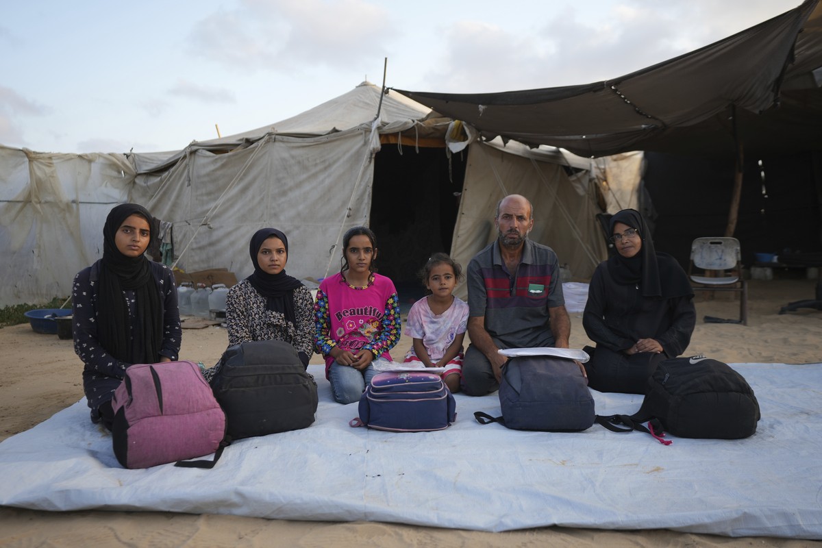 Members of the Abu Jarad family pose for a photo in their tent camp, where they now live after being displaced over five times since the start of the Israel-Hamas war, in Muwasi, Gaza Strip, Friday, S ...