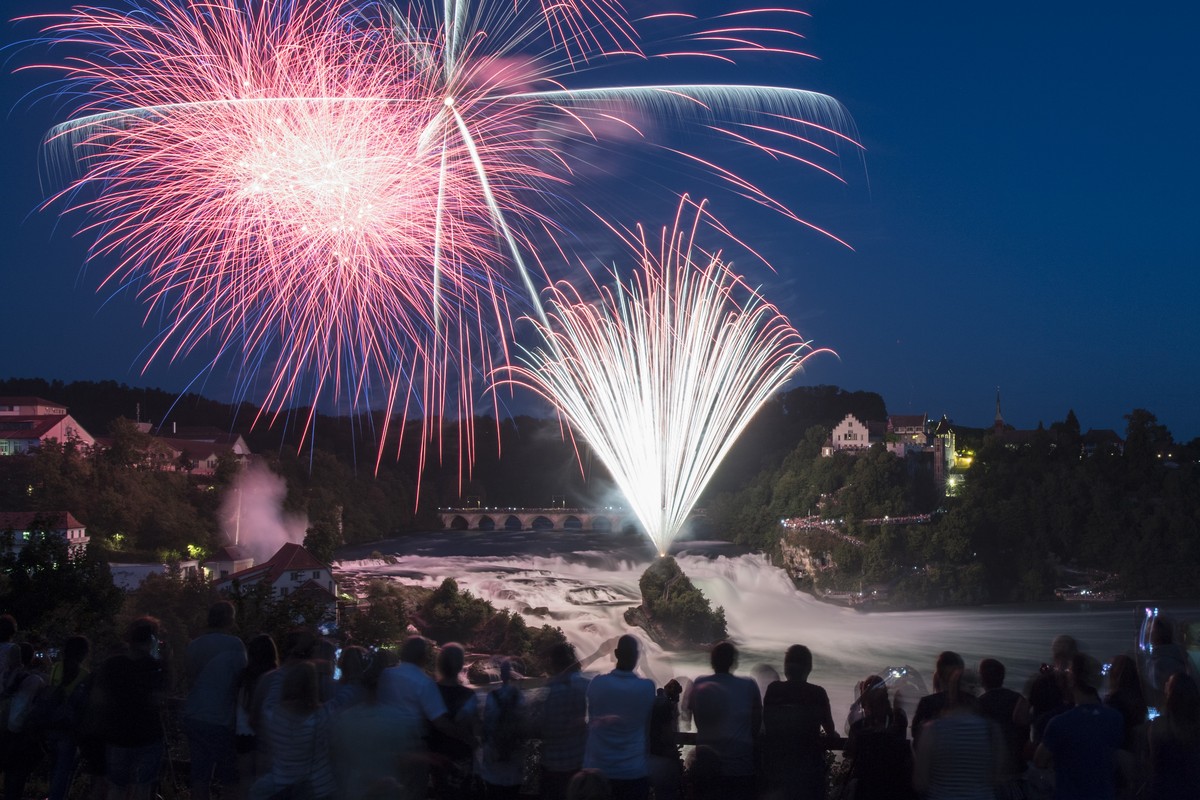 Menschen betrachten das Feuerwerk "Fire on the rocks" am Himmel ueber dem Rheinfall, anlaesslich des Nationalfeiertags am ersten August, aufgenommen am Montag, 31. Juli 2017 in Neuhausen am  ...