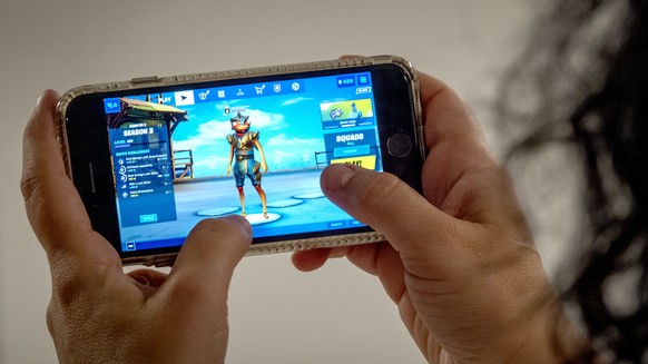 epa08621884 A person plays Fortnite on an iPhone in Miami, Florida, USA, 24 August 2020. US tech giant Apple and game developer Epic Games are in a dispute over the distribution of income from in-app  ...