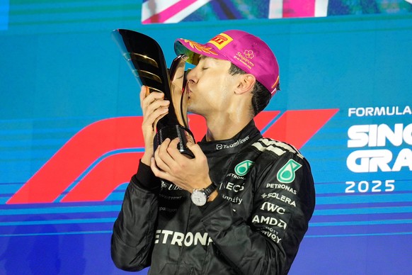 Mercedes driver George Russell of Britain kisses his trophy as he celebrates after winning the Singapore Formula One Grand Prix at the Marina Bay Street Circuit in Singapore, Sunday, Oct. 5, 2025. (AP ...