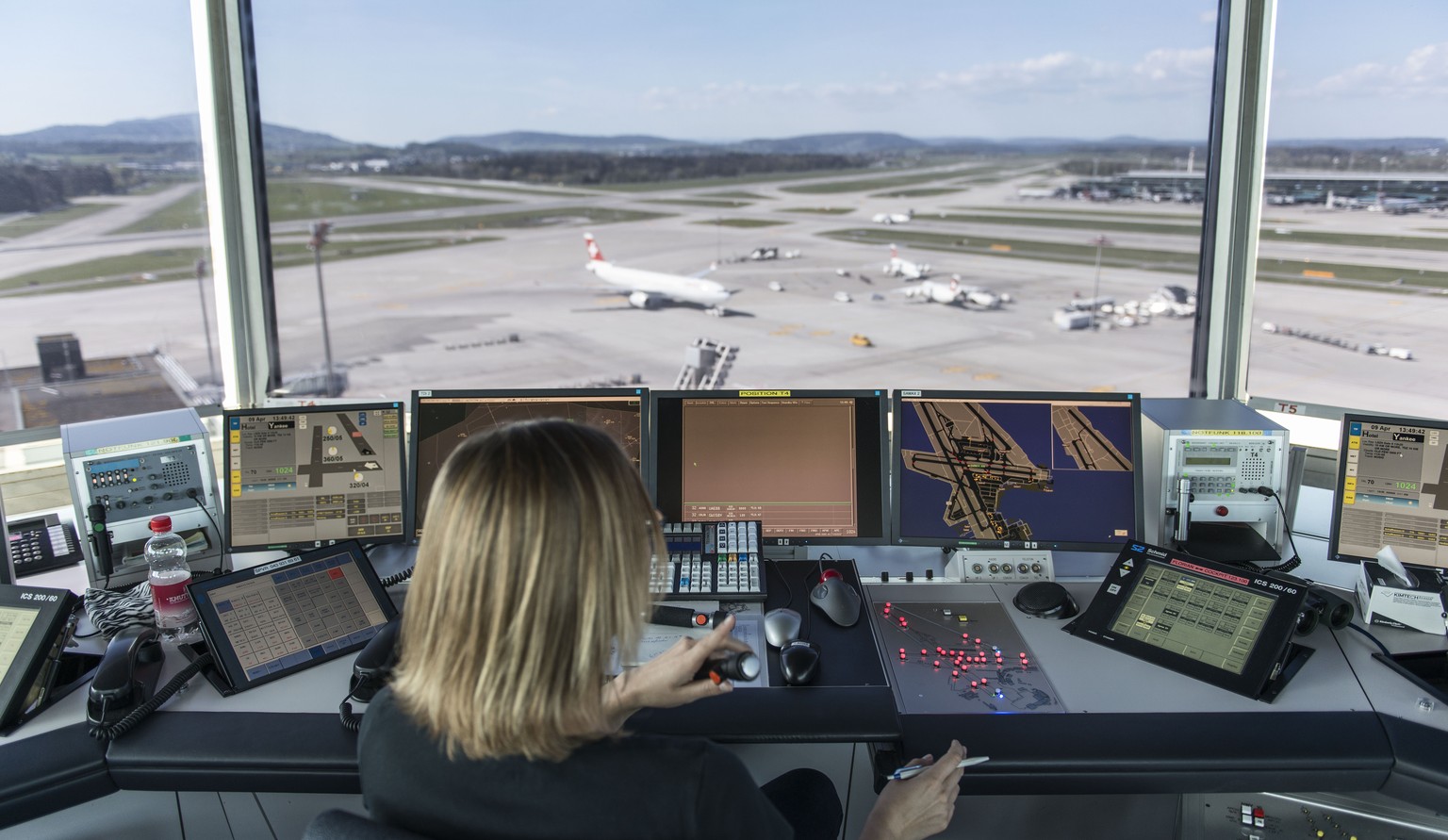 Eine Mitarbeiterin von Skyguide kontrolliert die Monitore und hat Blick auf das Flugfeld.