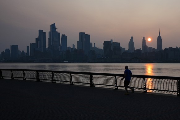 A runner trots at Pier A Park in Hoboken, N.J., as the sun rises behind the New York City skyline on the day of the World Cup final soccer match between Spain and Argentina to be played in East Ruther ...