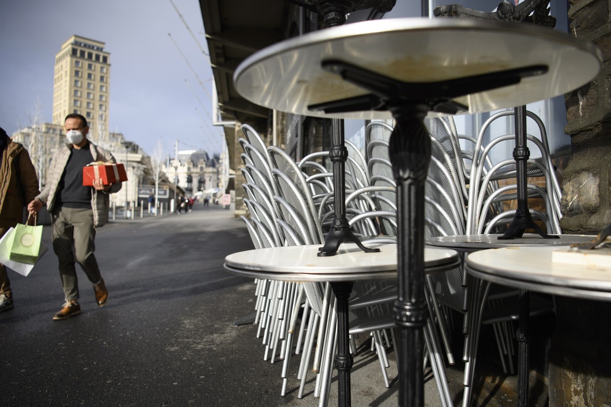epa08899435 People wearing protective face mask walk next to a closed restaurant terrace during their Christmas shopping amidst the coronavirus disease (COVID-19) outbreak, in Lausanne, Switzerland, 2 ...