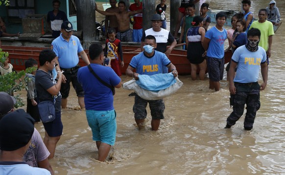 epa06403874 A Filipino policeman carries a body of a victim on floodwater in flood hit town of Salvador, Lanao del Norte province, Philippines, 23 December 2017. According to news reports, Tropical st ...