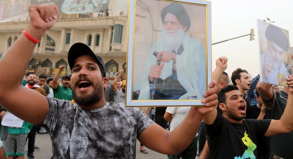 epa09978100 Supporters of Sadrist movement carry the pictures of Muqtada al-Sadr and his father Mohammed Sadiq al-Sadr during a gathering at the Al-Tahrir square in central Baghdad, Iraq, 26 May 2022. ...