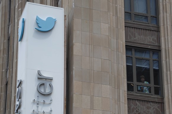 epa10766829 An employee peers out of a window near the iconic vertical Twitter sign at the company?s headquarters after work was halted on the altering of the sign in San Francisco, California, USA, 2 ...