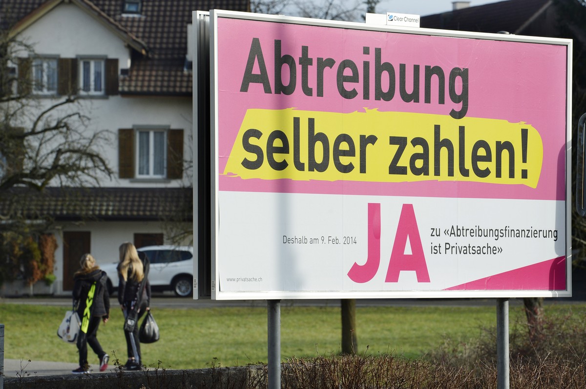 Passantinnen gehen an einem Plakat mit der Aufschrift "Abtreibung selber zahlen-JA" der Befuerworter der Abtreibungsfinanzierungsinitiative vorbei, aufgenommen am Sonntag, 12.Januar 2014, in ...