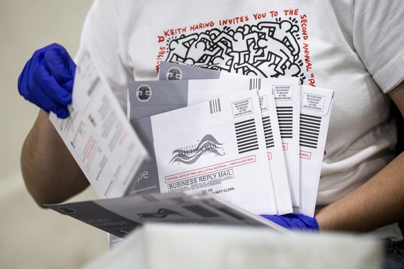 epa08794391 An election worker checks the signatures on mail-in ballots and for irregularities at the Los Angeles County Registrar Recorders' mail-in ballot processing center at the Pomona Fairpl ...