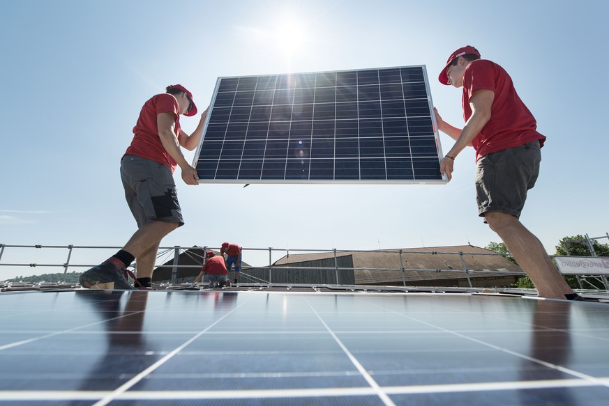 ZUR EIDGENOESSISCHEN ABSTIMMUNG VOM 21. MAI 2017 UEBER DAS ENERGIEGESETZ STELLEN WIR IHNEN ZUM THEMA SOLARENERGIE FOLGENDES BILDMATERIAL ZUR VERFUEGUNG  Solarmodule werden auf einem Dach montiert, au ...