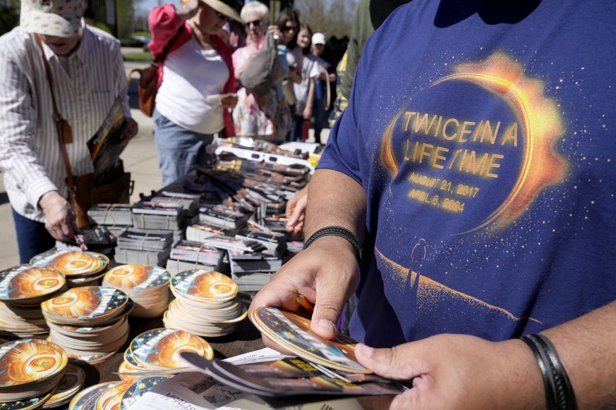 Spectators grab solar glasses and other mementos as they enter Saluki Stadium to watch the total solar eclipse Monday, April 8, 2024, in Carbondale, Ill. (AP Photo/Jeff Roberson)