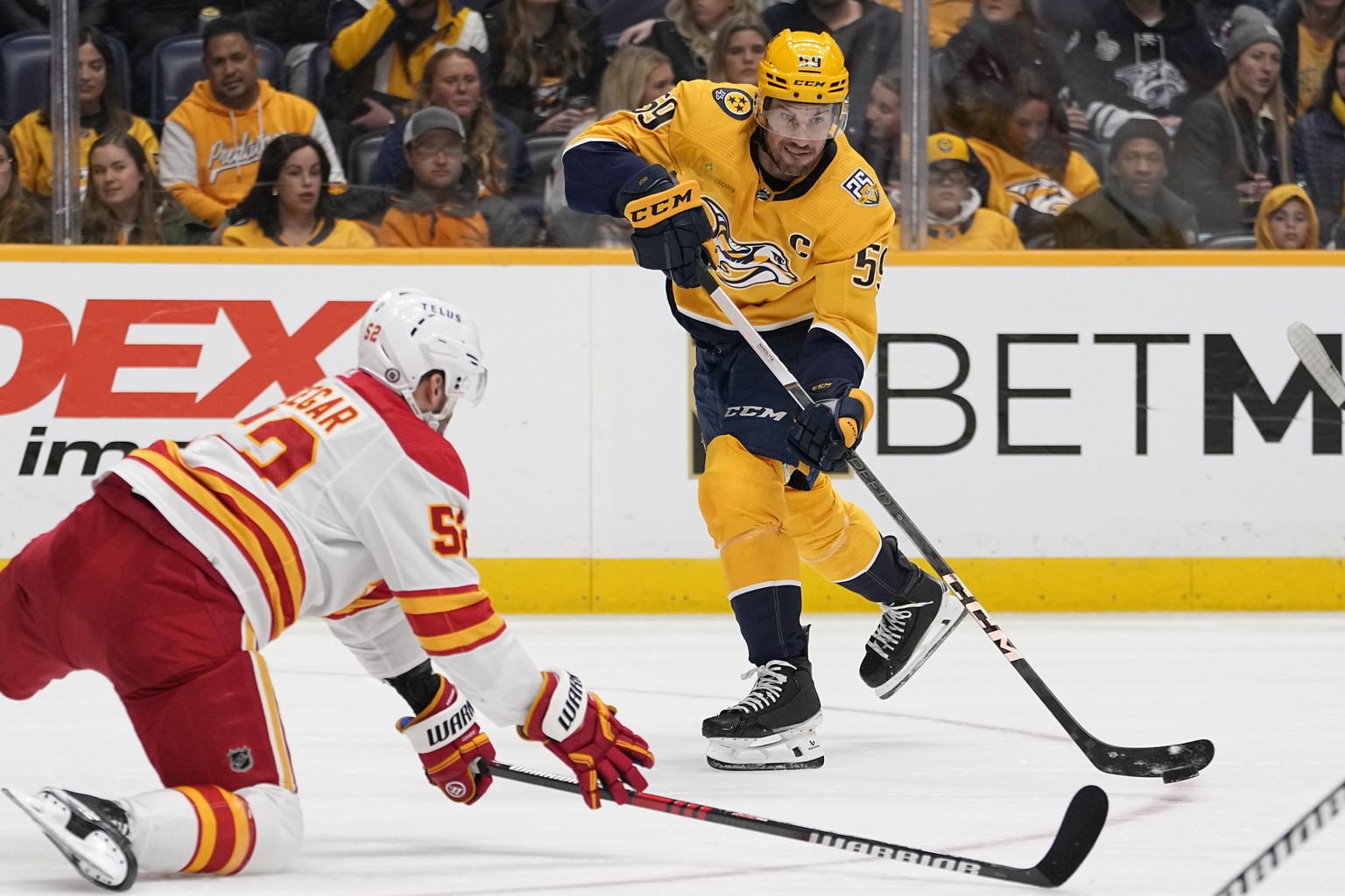 Nashville Predators defenseman Roman Josi (59) passes the puck past Calgary Flames defenseman MacKenzie Weegar, left, during the second period of an NHL hockey game Wednesday, Nov. 22, 2023, in Nashvi ...