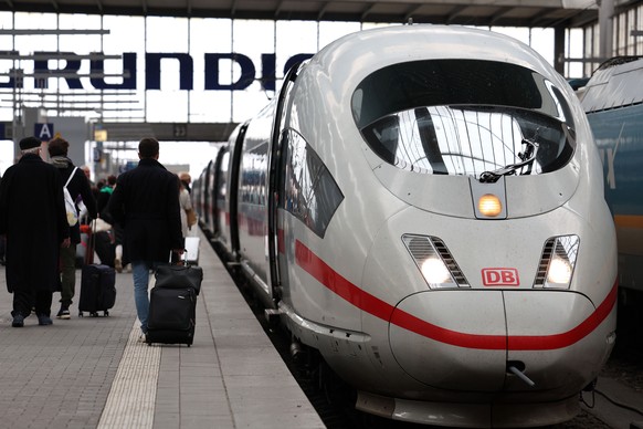epa10543754 Passengers walk by a train at the Munich Central Train Station one day prior the transportation strike in Munich, Germany, 26 March 2023. Deutsche Bahn announced that all long-distance tra ...