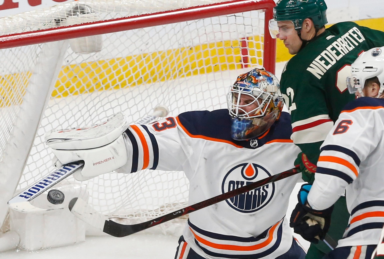 Edmonton Oilers&#039; goalie Cam Talbot, left, blocks a shot as Minnesota Wild&#039;s Nino Niederreiter of Switzerland tried to bat the airborne puck into the net in the third period of an NHL hockey  ...