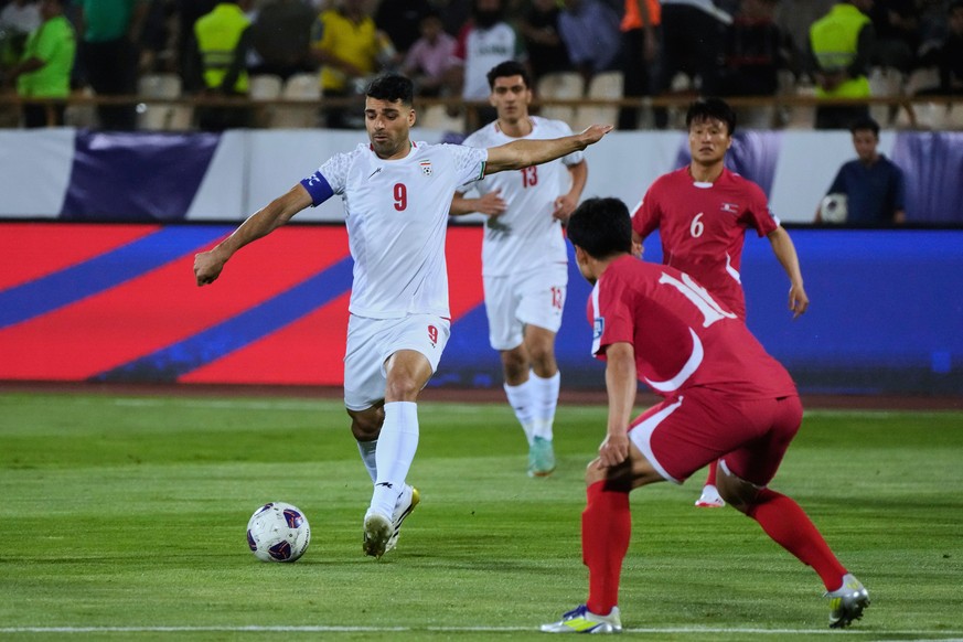 Iran's Mehdi Taremi, left, attempts a shot on North Korea's goal during their Asian qualifier group A soccer match for the 2026 World Cup, Tuesday, June 10, 2025, at Azadi Stadium in Tehran, ...