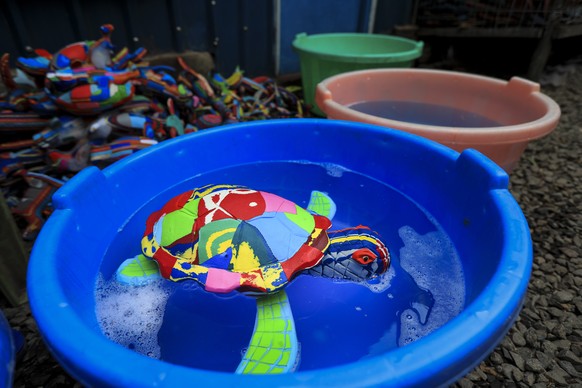 epa10228975 A sea-turtle figure made from old flip-flops floats in a bucket where it is cleaned before drying at the workshop of the Kenyan social enterprise &#039;Ocean sole&#039; in Nairobi, Kenya,  ...