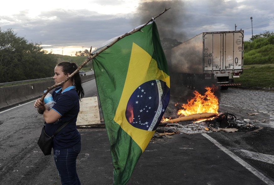 epa10277722 A woman holds a Brazilian flag during a trucker&#039;s blockade today, on the Presidente Dutra highway, near Volta Redonda, Brazil, 31 October 2022. The Bolsonaro protesters blocked dozens ...