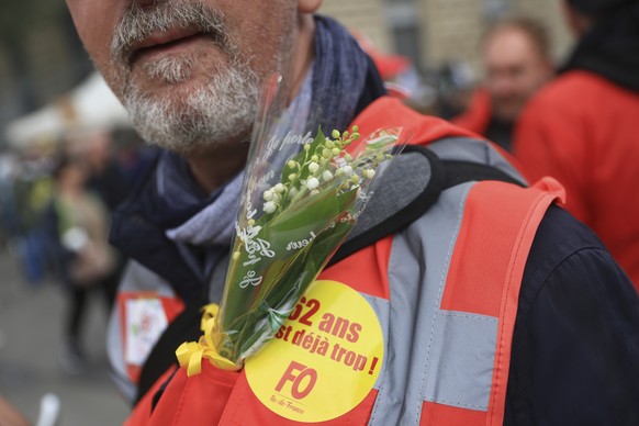 An unionist displays the traditional Lily of the Valley flower on his jacket during a demonstration, Monday, May 1, 2023 in Paris. French unions plan massive demonstrations around France to protest Pr ...