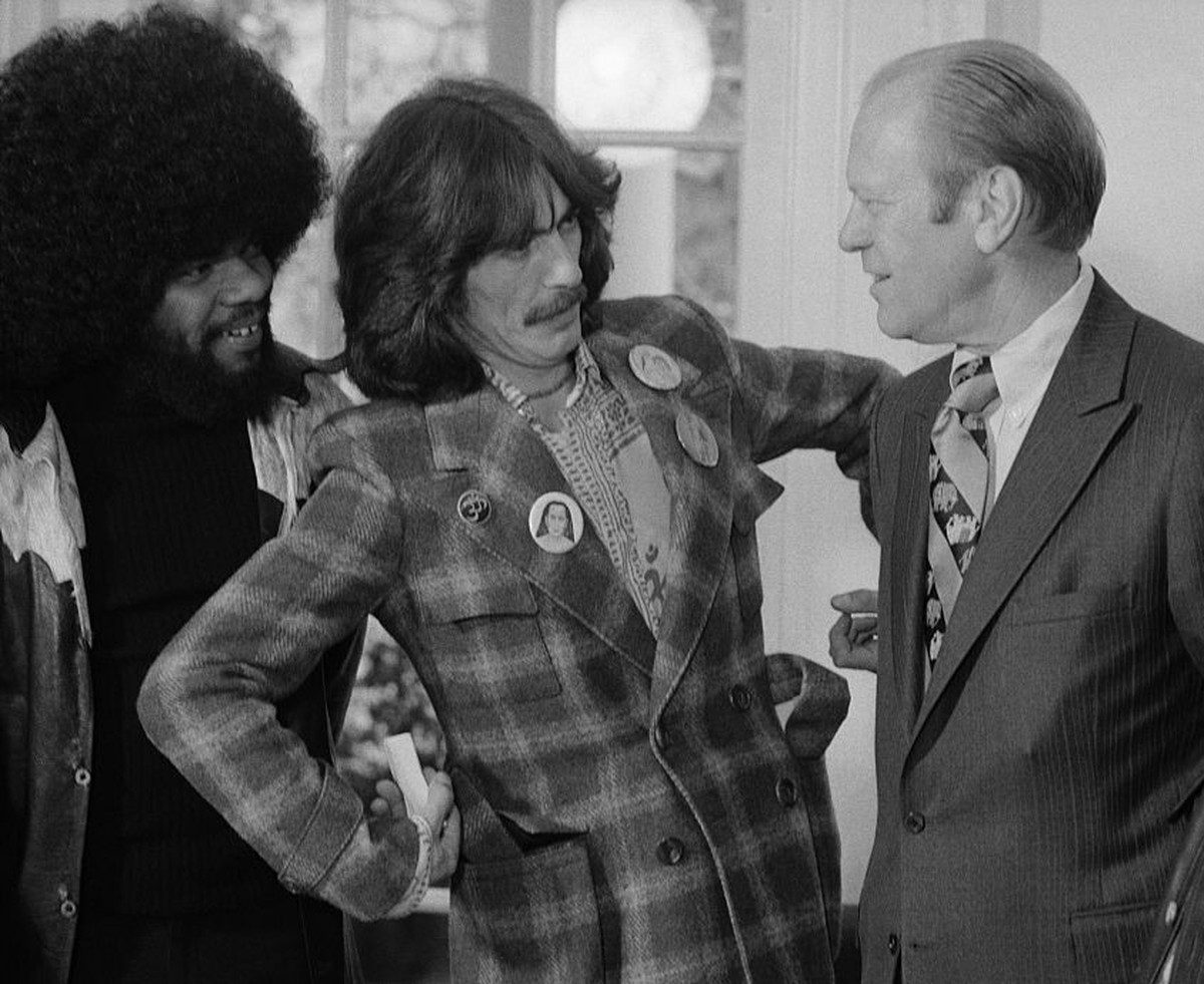 President Ford is greeted in the Oval Office of the White House, December 13th 1974, by former Beatle George Harrison, who was hosted to a luncheon at the White House by Ford's son, Jack. At left ...