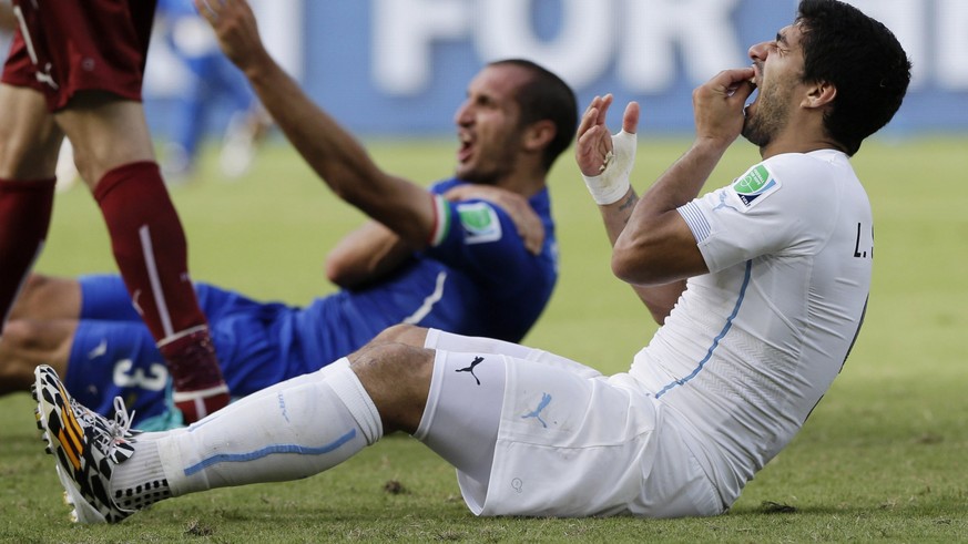 FILE - In this June 24, 2014 file photo, Uruguay&#039;s Luis Suarez holds his teeth after biting Italy&#039;s Giorgio Chiellini&#039;s shoulder during the group D World Cup soccer match between Italy  ...