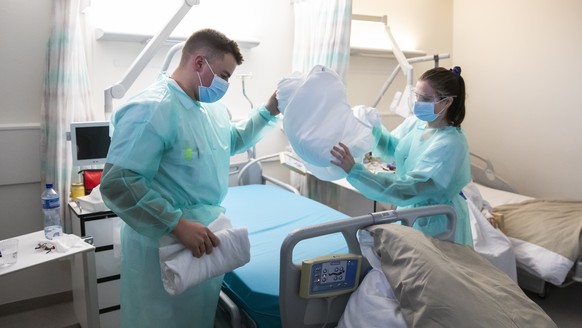 Ein Sanitaetssoldat und eine Pflegerin machen das Bett einer Covid-19 Patientin im Kantonsspital Fribourg HFR, am Donnerstag, 12. November 2020 in Fribourg. Angesichts der sanitaeren Lage und der Zuna ...