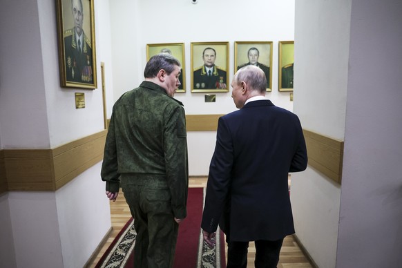 Russian President Vladimir Putin, right, and Russian Chief of General Staff Gen. Valery Gerasimov talk to each other as they walk through a corridor at the headquarters of Russia&#039;s Southern Milit ...