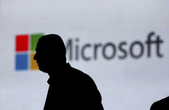 FILE - In this Nov. 7, 2017, file photo, a man is silhouetted as he walks in front of Microsoft logo at an event in New Delhi, India. Microsoft says it’s uncovered new Russian hacking attempts targeti ...