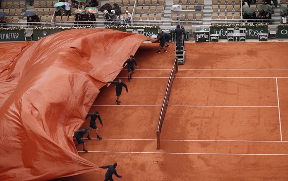 epa07633301 Staff covers the Court Philippe Chatrier as rain interrupts Dominic Thiem of Austria playing Novak Djokovic of Serbia during their menâs semi final match during the French Open tennis to ...