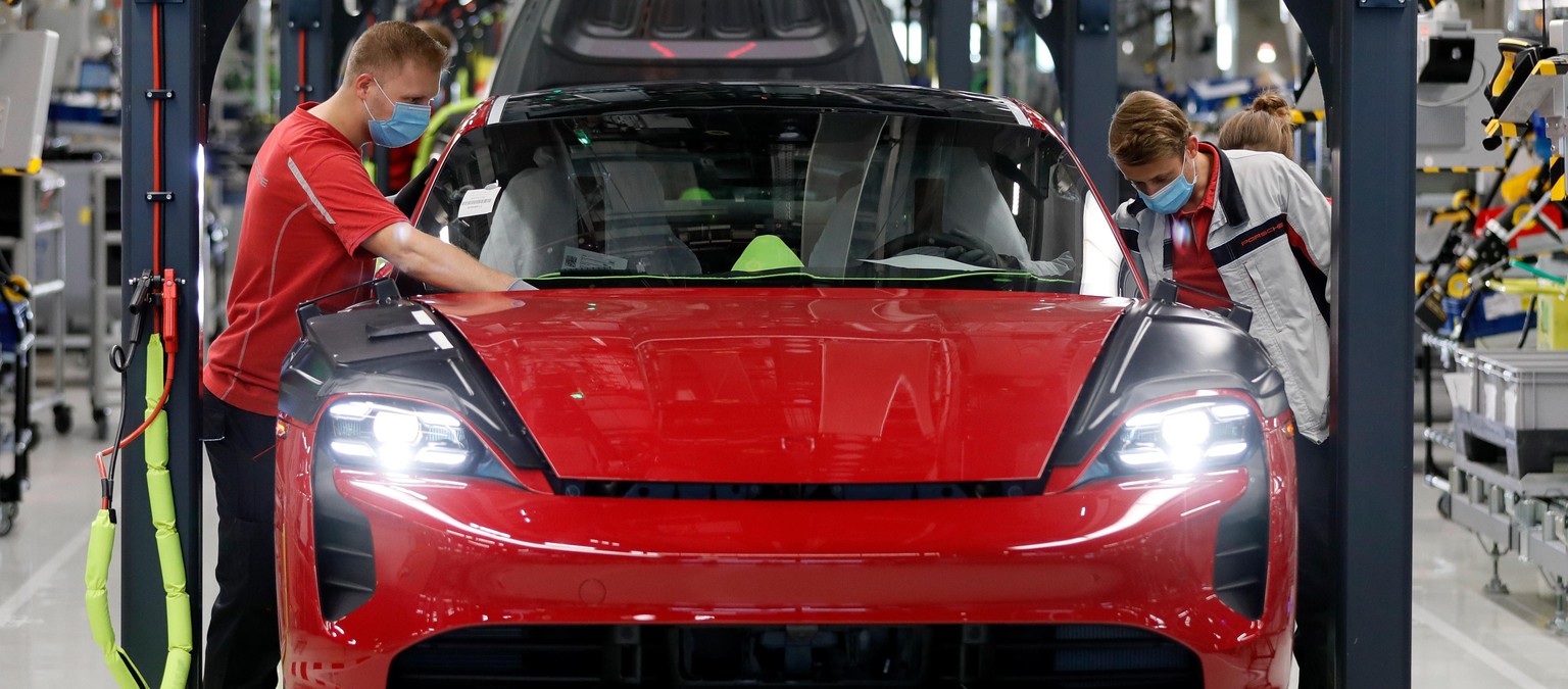 epa08416418 Workers wearing protective face masks and gloves work in the production of the &#039;Taycan&#039; electric sports cars at an assembly line of German car manufacturer Porsche in Stuttgart,  ...