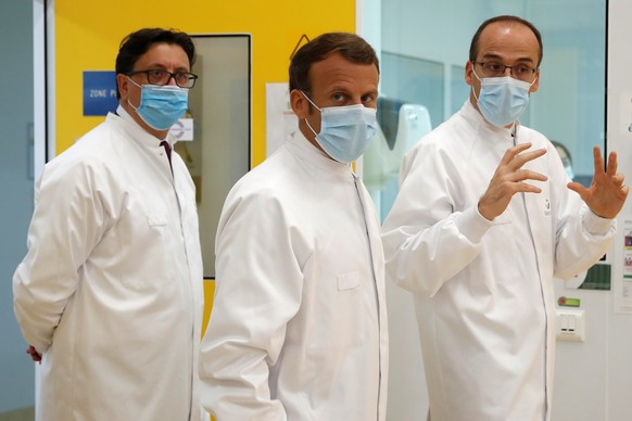 epa08487818 French President Emmanuel Macron, Thomas Triomphe, Executive Vice President of Sanofi Pasteur, and Paul Hudson, Chief Executive Officer of Sanofi, wearing protective face masks, visit an i ...