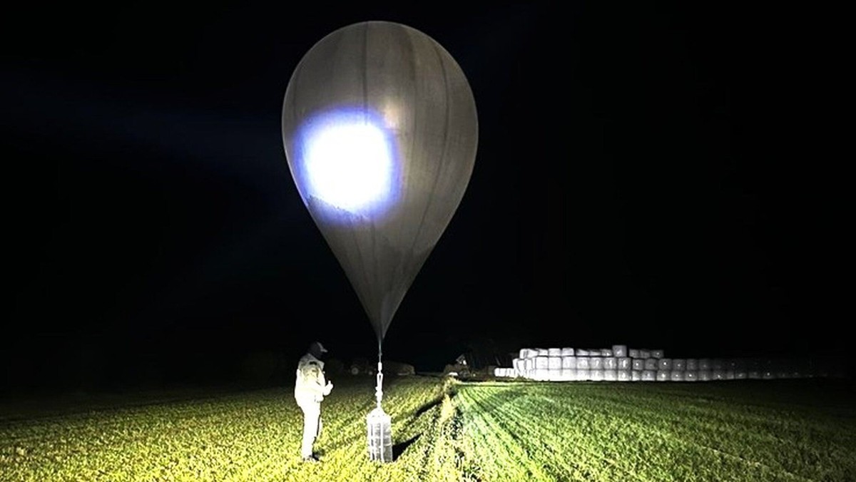 In this undated photo released by the State Border Guard Service, an officer inspects a balloon used to carry cigarettes into Lithuania, because Belarussian smugglers often use them to ferry the contr ...