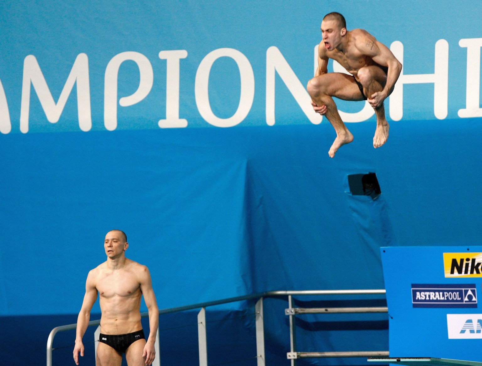 epa00960737 Russian diver Aleksander Dobroskok (L) looks over the side but fails to dive as his synchronised diving partner Gleb Galperin (R) dives with a shocked face as the Russians see their leadin ...
