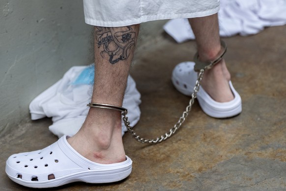 A prisoner with a tattoo with leg irons on stands as Homeland Security Secretary Kristi Noem tours the Terrorist Confinement Center in Tecoluca, El Salvador, Wednesday, March 26, 2025. (AP Photo/Alex  ...